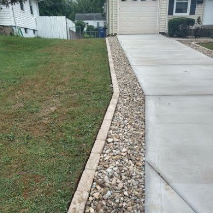 A concrete driveway leading to a house with a gravel border.