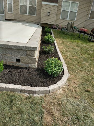 A backyard with a brick wall and a planter filled with plants.