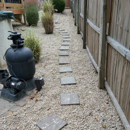 A swimming pool filter is sitting next to a wooden fence.