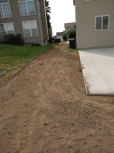 A dirt road leading to a house with a concrete driveway.