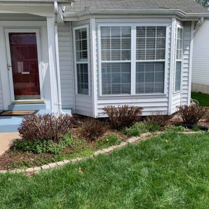 A white house with a large bay window and a red door.