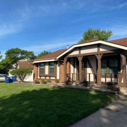 A house with a porch and a lot of grass in front of it.