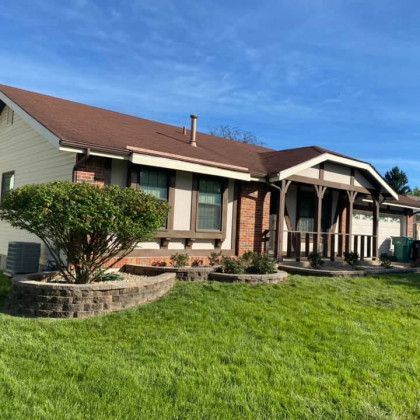 A house with a porch and a large lawn in front of it.