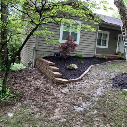 A house with a brick wall and stairs in front of it.
