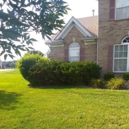 A brick house with a lush green lawn in front of it.