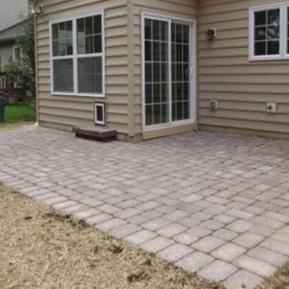 There is a patio in front of a house with sliding glass doors.
