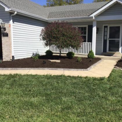 A house with a lush green lawn and a walkway in front of it.