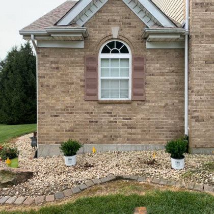 A brick house with a window and potted plants in front of it.