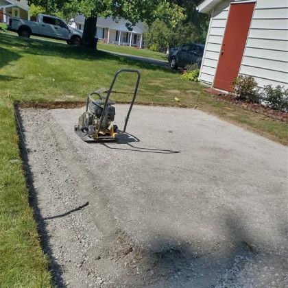 A vibratory plate compactor is sitting on top of a concrete surface.