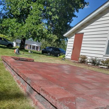 A brick patio is being built in front of a house.