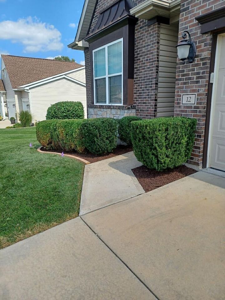 A brick house with a lush green lawn and a sidewalk in front of it.