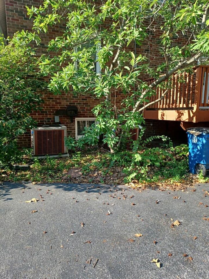 A brick house with a blue trash can in front of it.