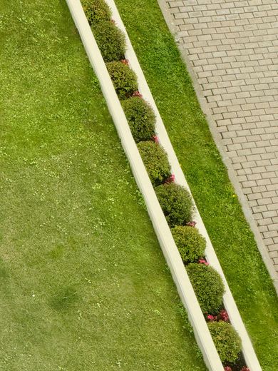 A house with a brick wall and a lawn mower in front of it.
