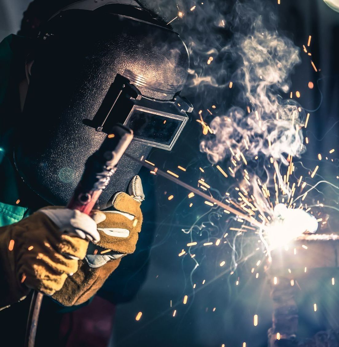A man wearing a welding mask is welding a piece of metal — Tinman's Welding Worx In Mackay, QLD