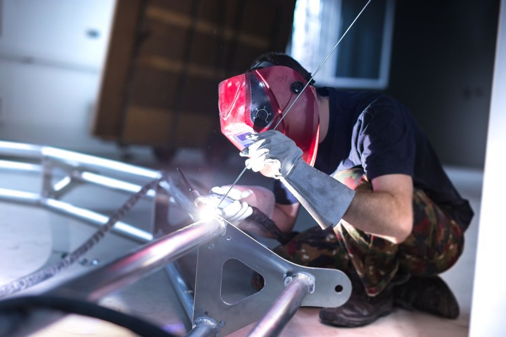 A Man Wearing A Welding Mask Is Welding A Piece Of Metal — Tinman's Welding Worx In Sarina, QLD