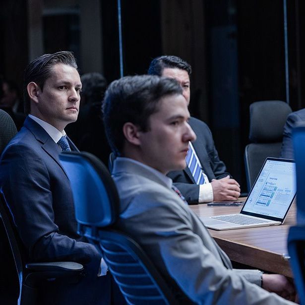 A group of men are sitting at a table with laptops.