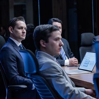 Un grupo de hombres está sentado en una mesa con computadoras portátiles.