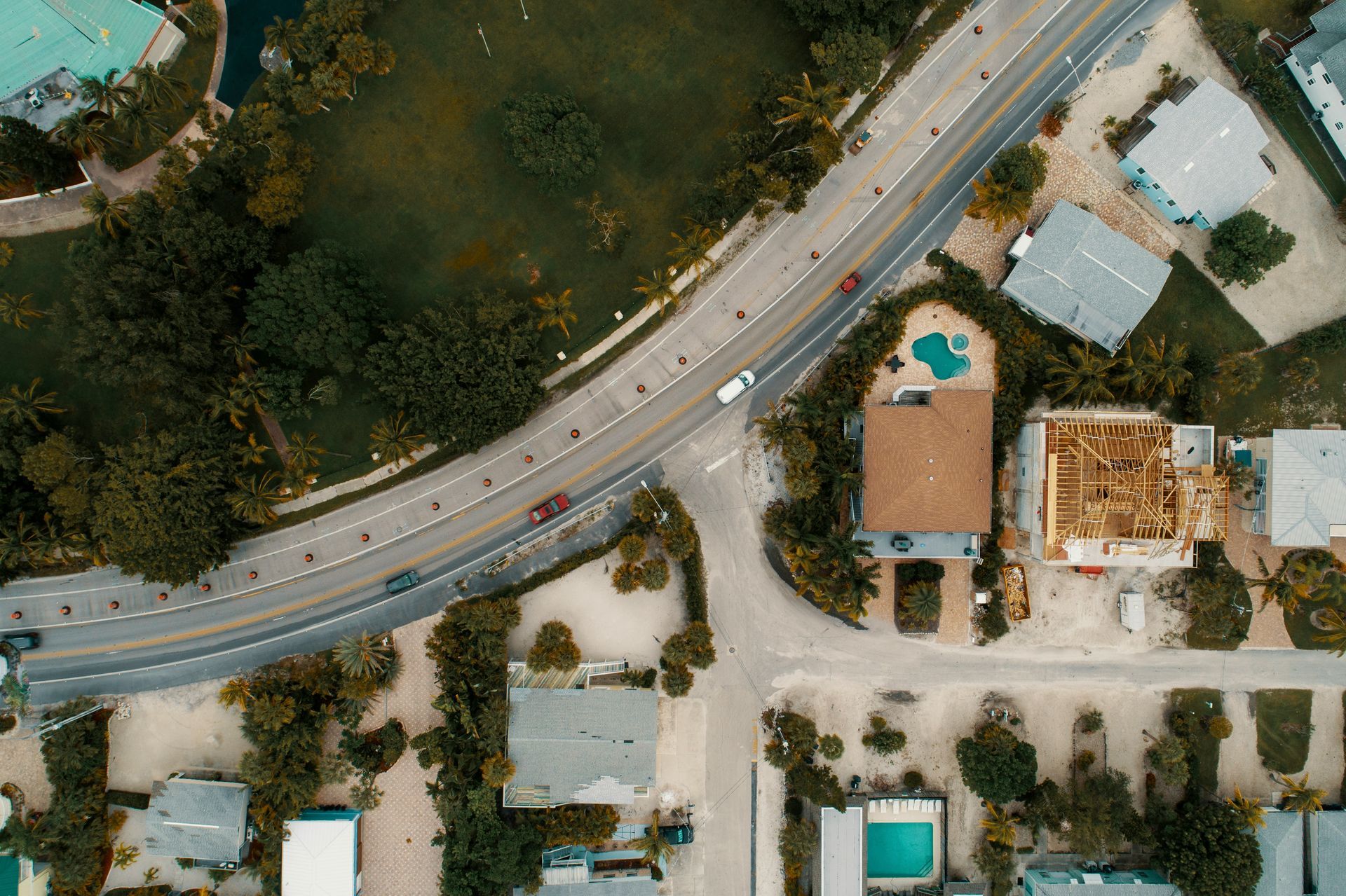 An aerial view of a road surrounded by houses and trees.