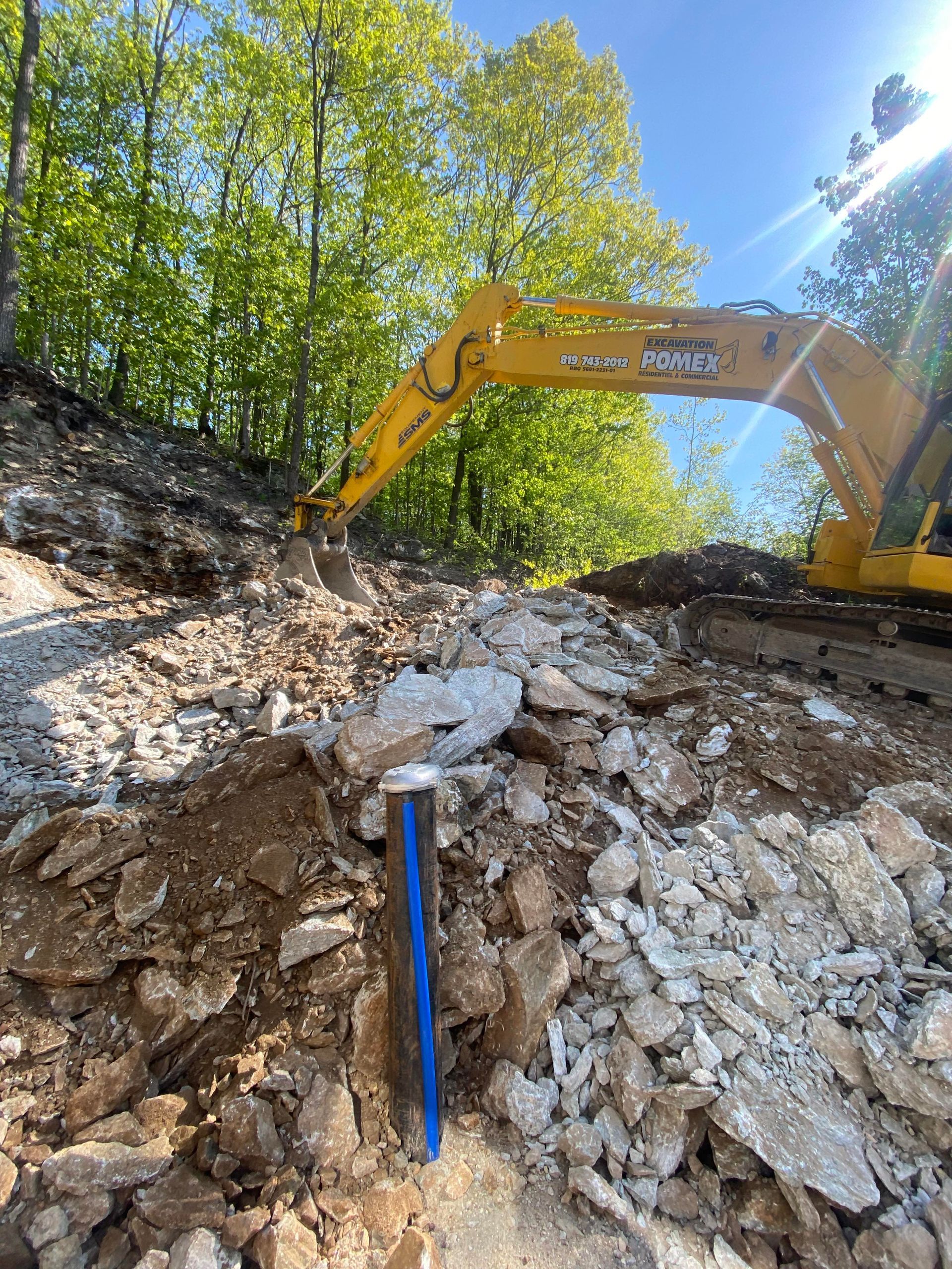 Une excavatrice jaune creuse un trou dans un tas de rochers.