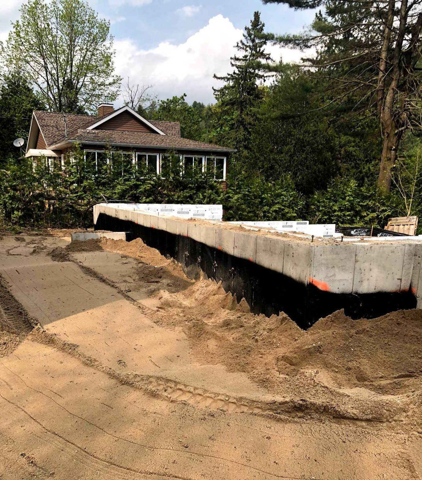 Un grand mur de béton est en train d'être construit devant une maison.