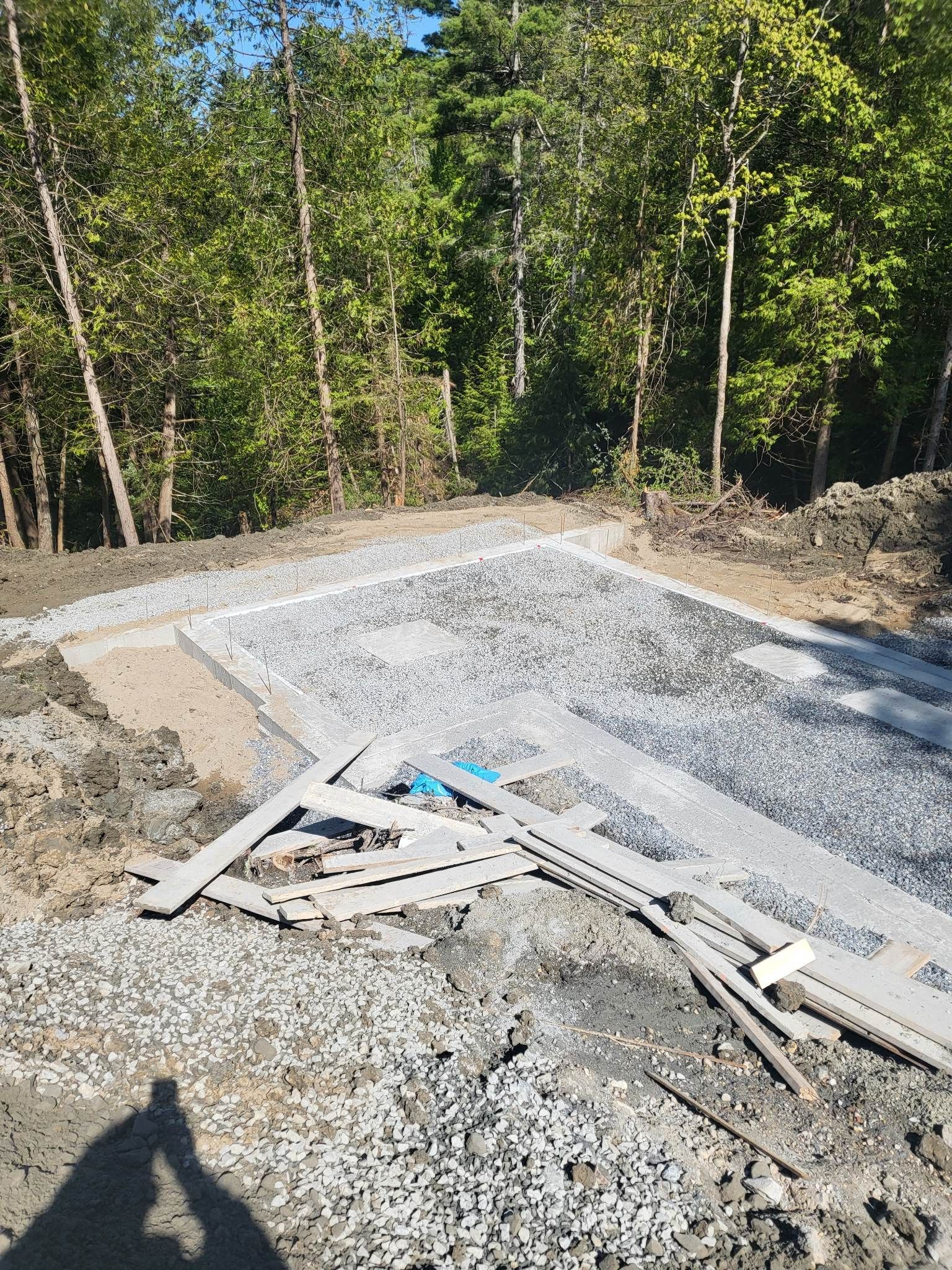 L'ombre d'une personne est projetée sur un chemin de gravier dans les bois.