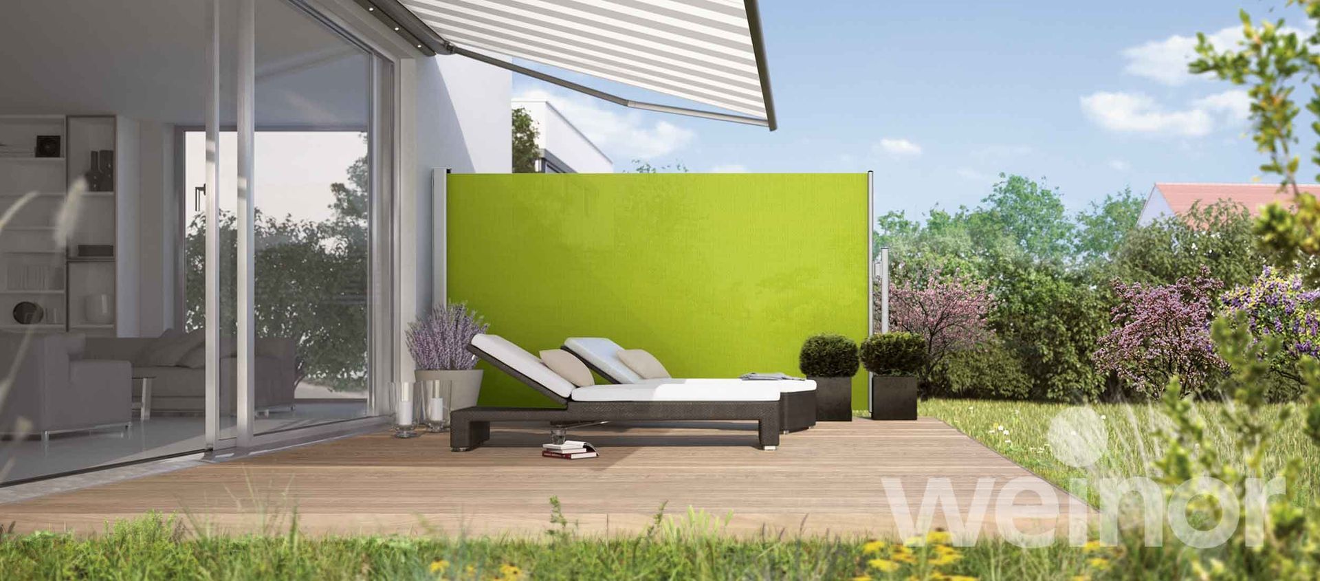 A patio with two lounge chairs and a green wall.