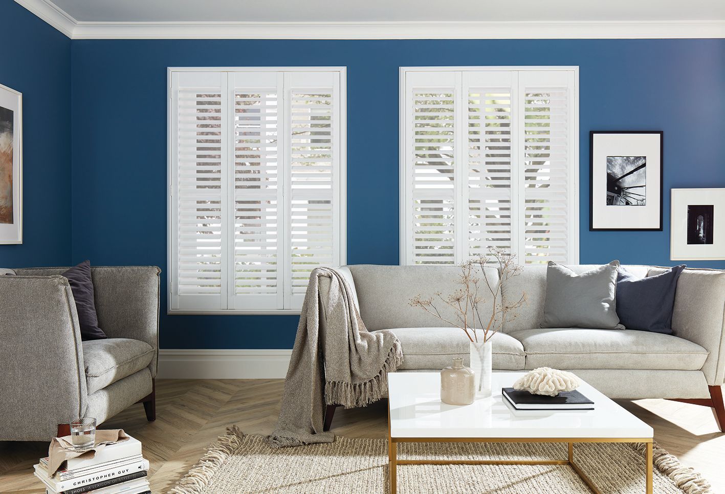 A living room with blue walls and white shutters on the windows.