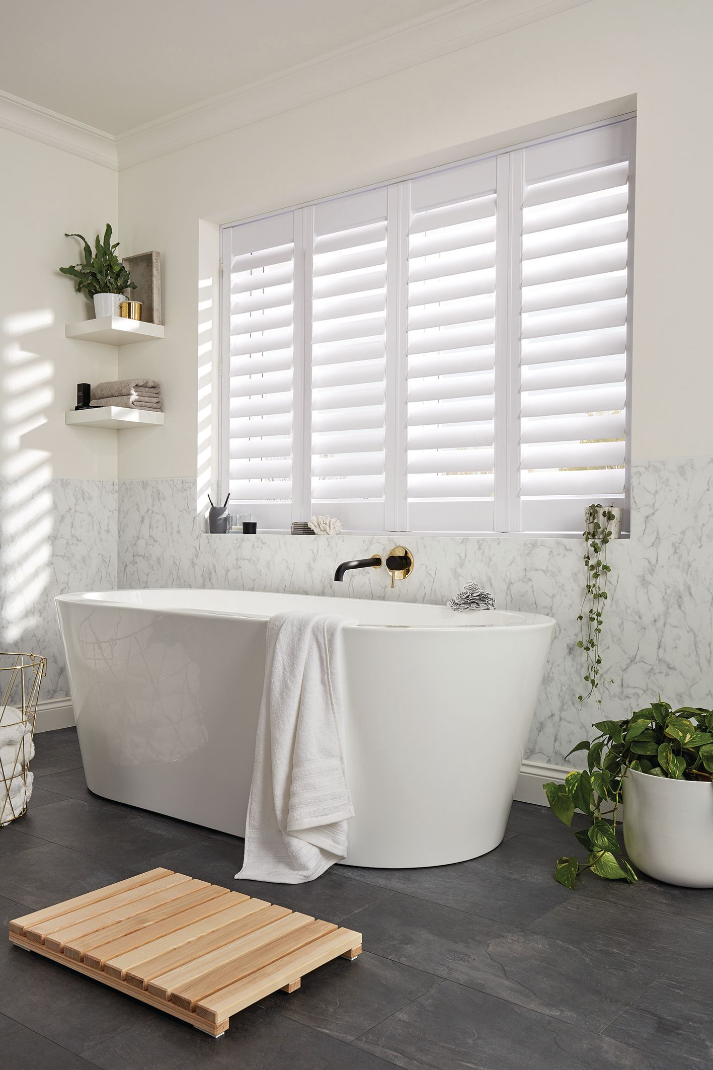 A bathroom with a bathtub and a window with white shutters.