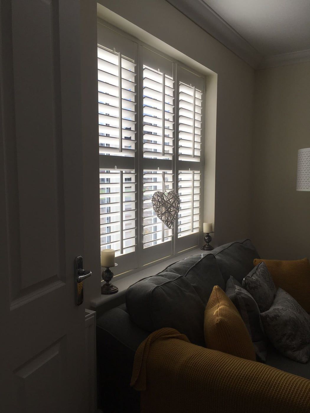 A living room with a couch and a window with shutters