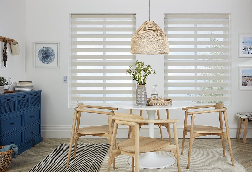 A dining room with a table and chairs and blinds on the windows.
