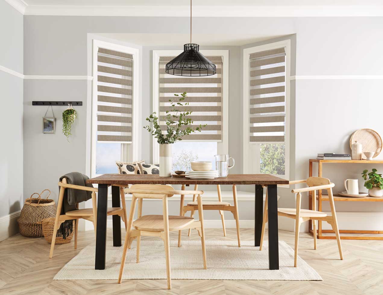 A dining room with a table and chairs and blinds on the windows.