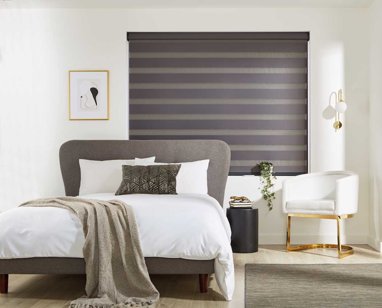 A bedroom with a bed , chair , rug and striped blinds.