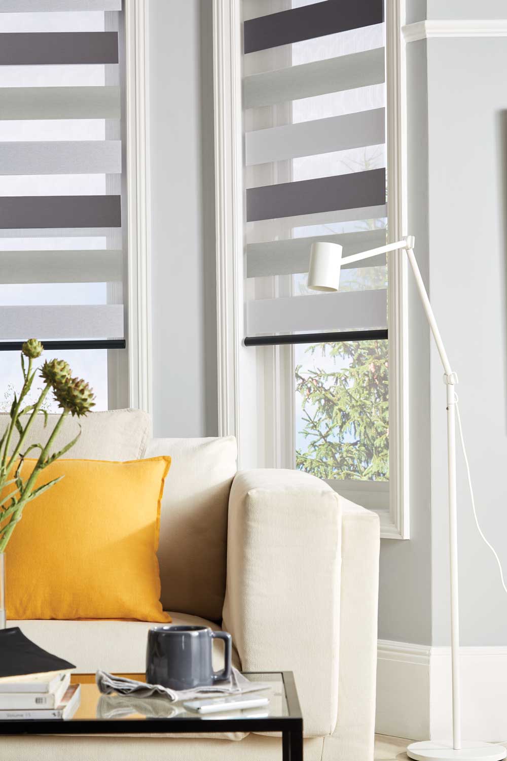 A living room with a couch , table , lamp and striped blinds.