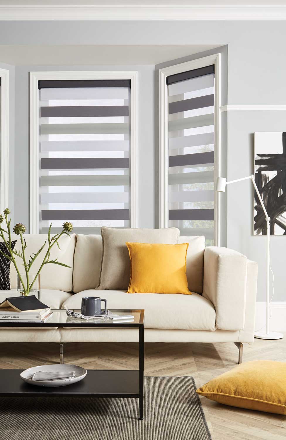 A living room with a couch , coffee table , and striped blinds.
