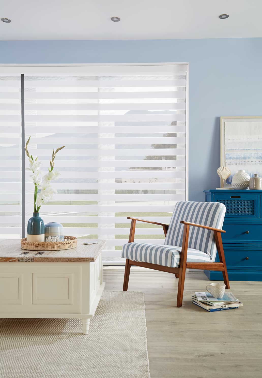 A living room with a chair , coffee table , and blue dresser.