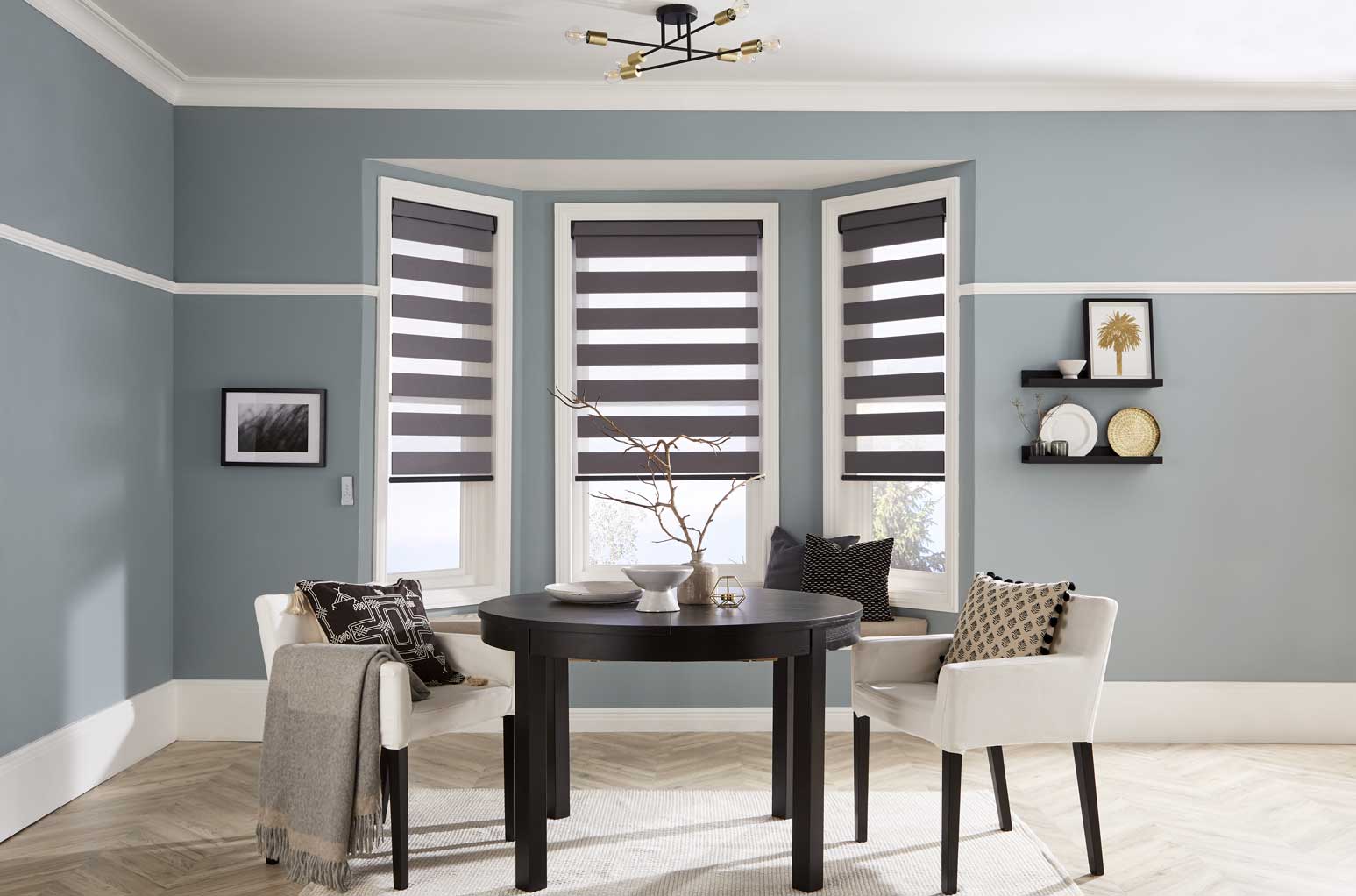 A dining room with a table and chairs and striped blinds on the windows.