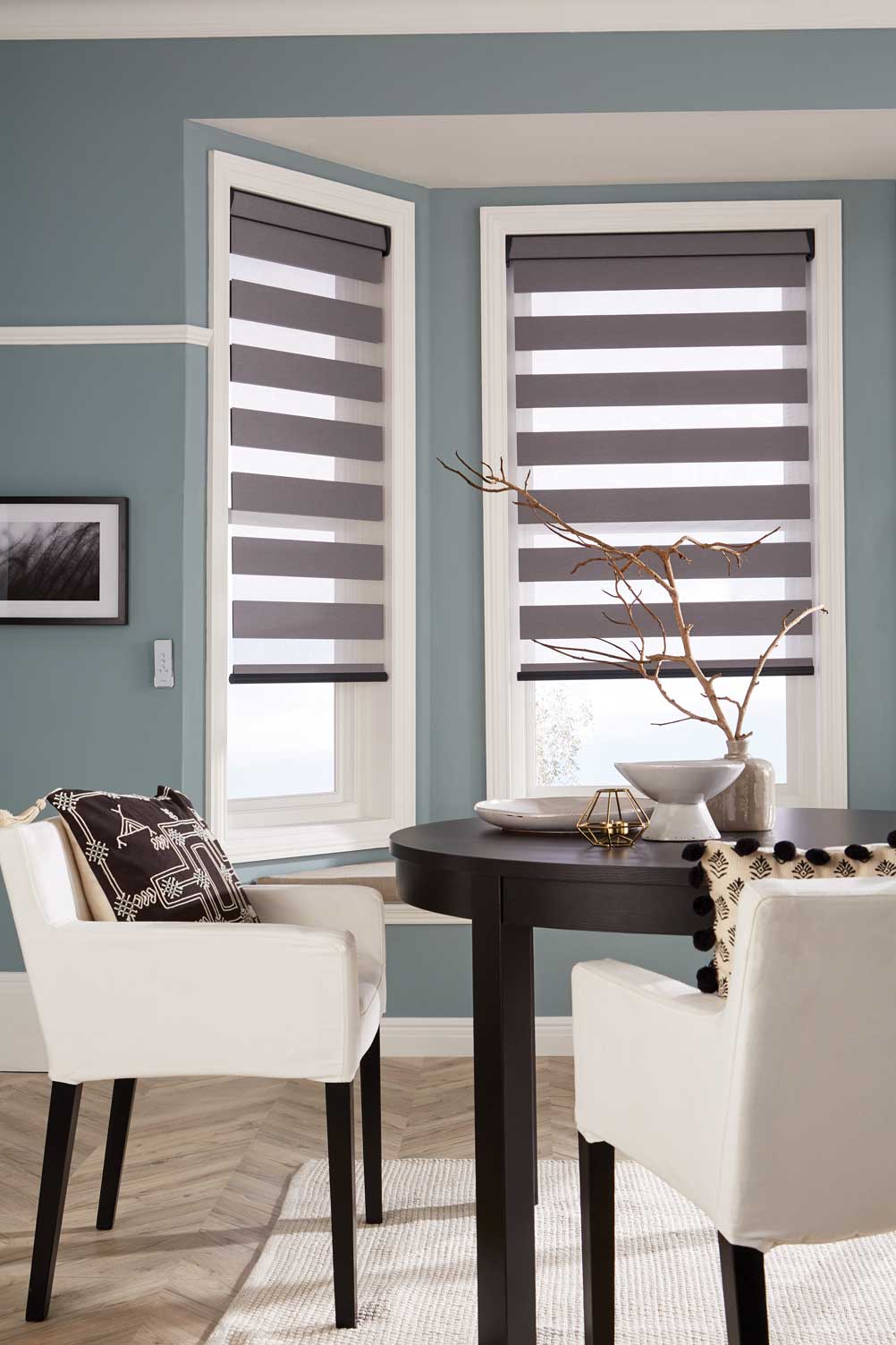 A dining room with a table and chairs and striped blinds on the windows.