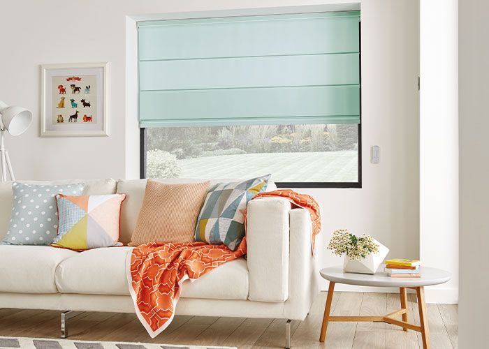 A living room with a white couch and a window with a blue blind.