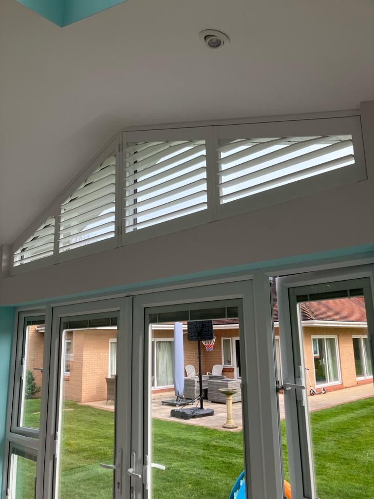 A room with a lot of windows and shutters on the ceiling.