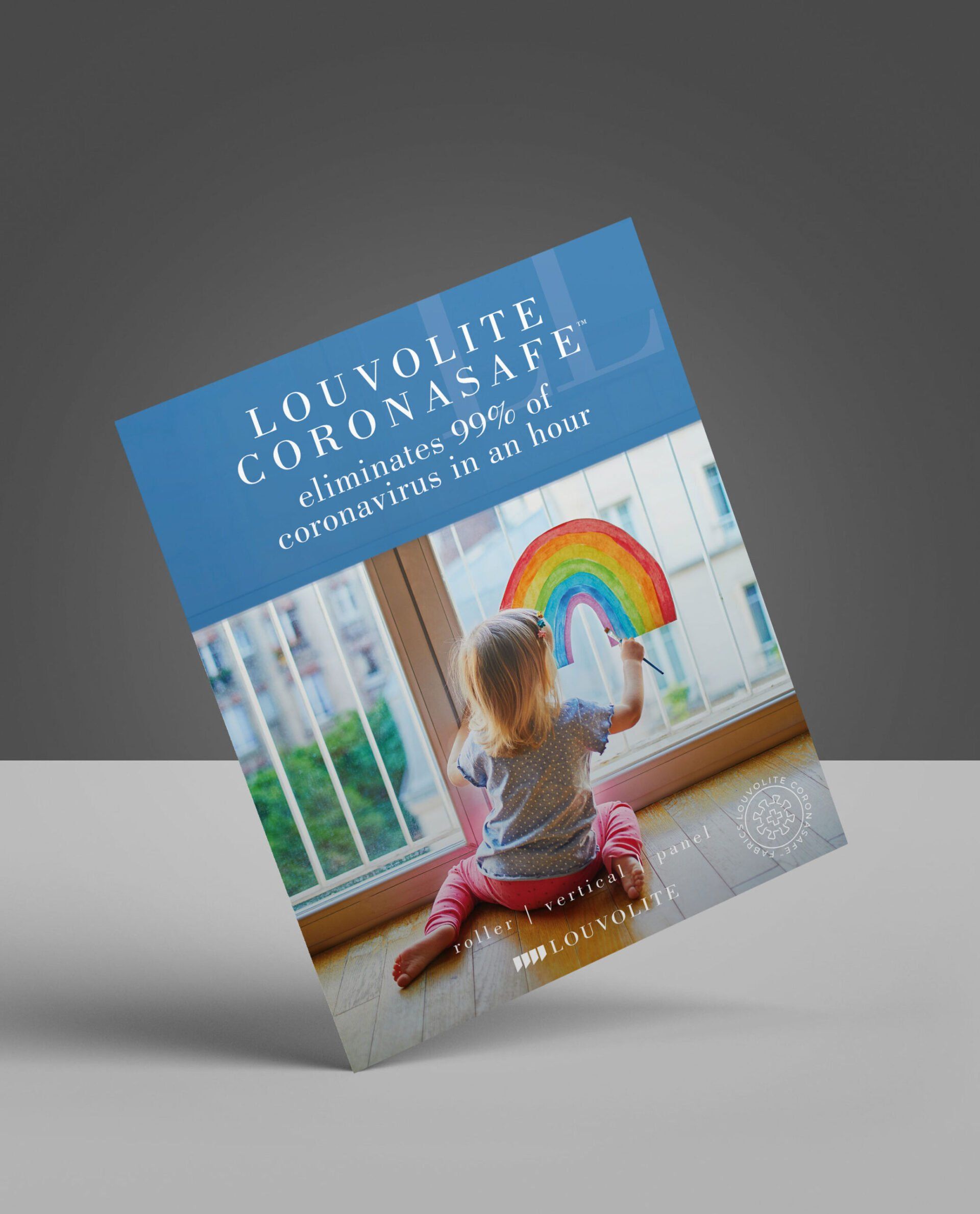 A little girl is sitting on the floor holding a rainbow in front of a window.