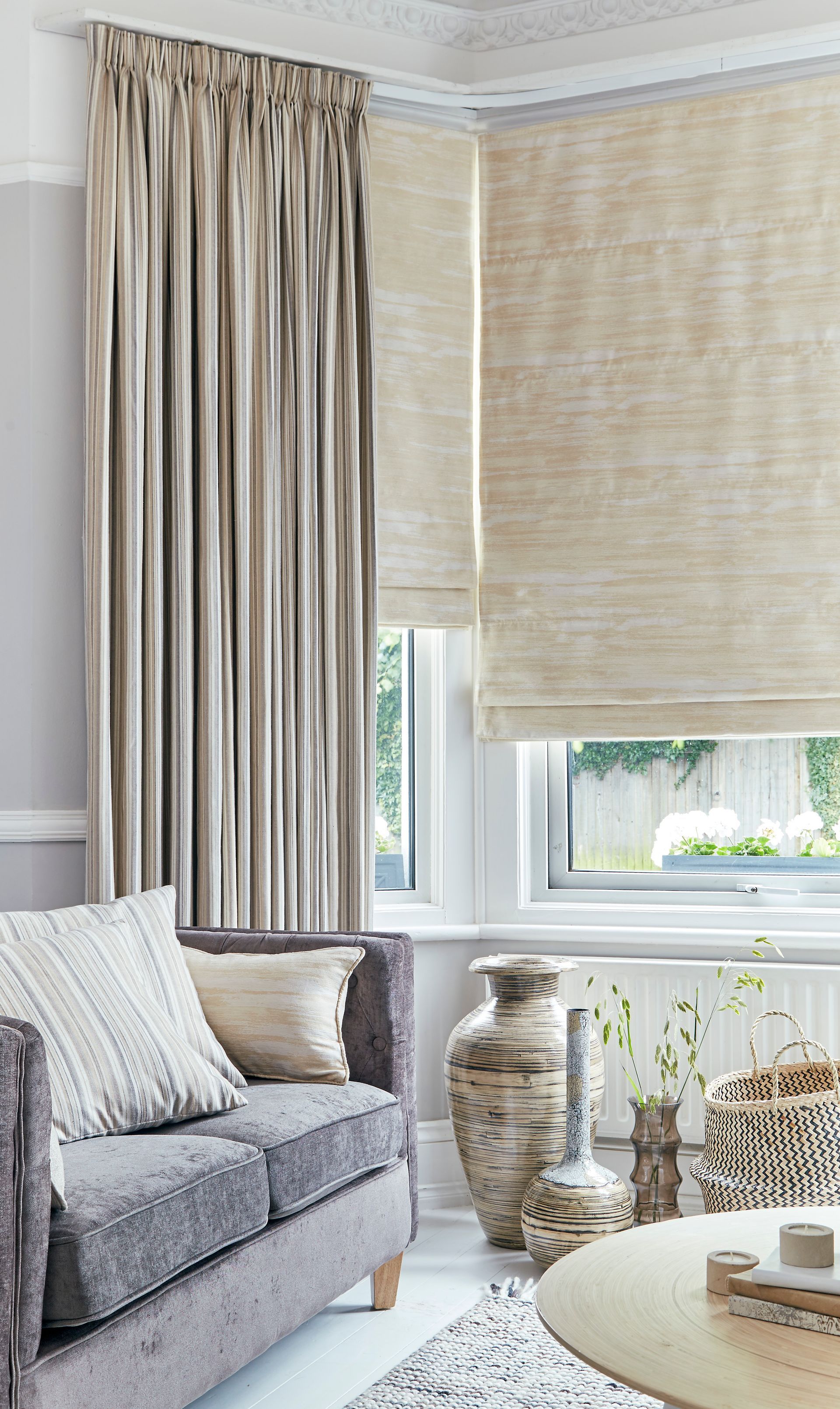 A living room with a couch , table , vases and curtains.