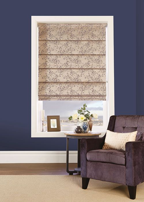 A living room with a chair and a window with roman shades.