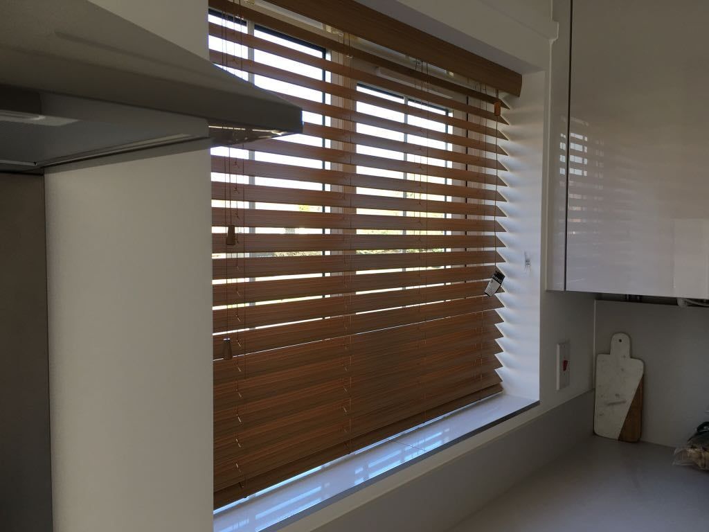 A kitchen window with wooden blinds on it