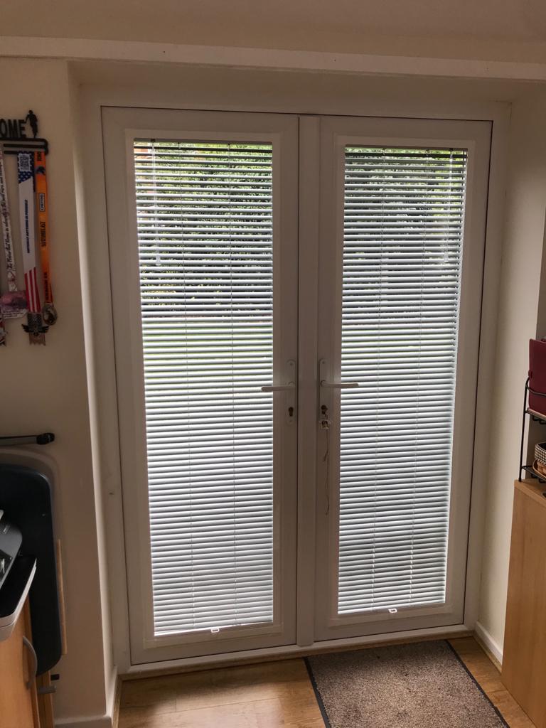 A pair of sliding glass doors with blinds on them in a room.