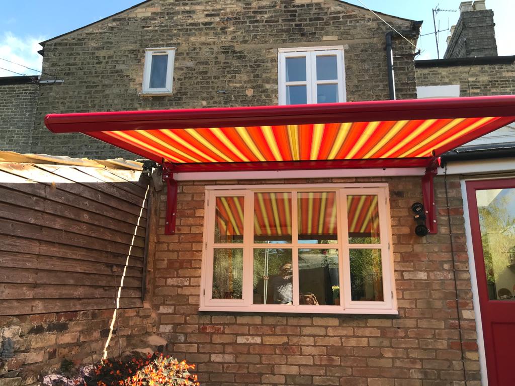 A red awning is hanging over a window on the side of a brick building.