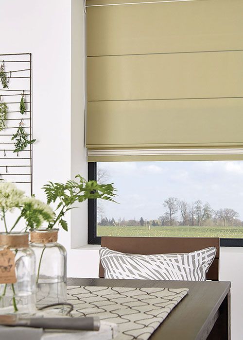 A dining room with a table and chairs and a window with a roman shade.
