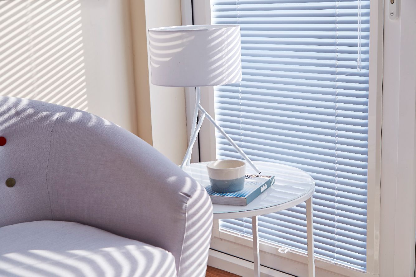 A chair is sitting next to a table with a lamp and a book on it.