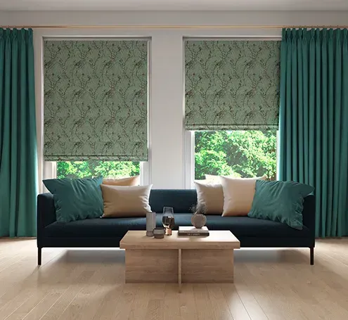 A living room with a couch , table , and two windows with green curtains.