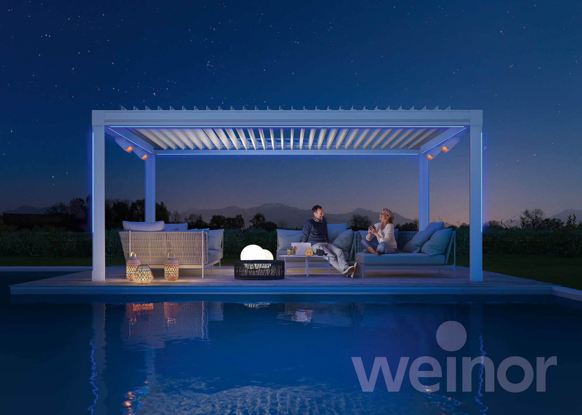 A couple is sitting under a pergola next to a swimming pool.