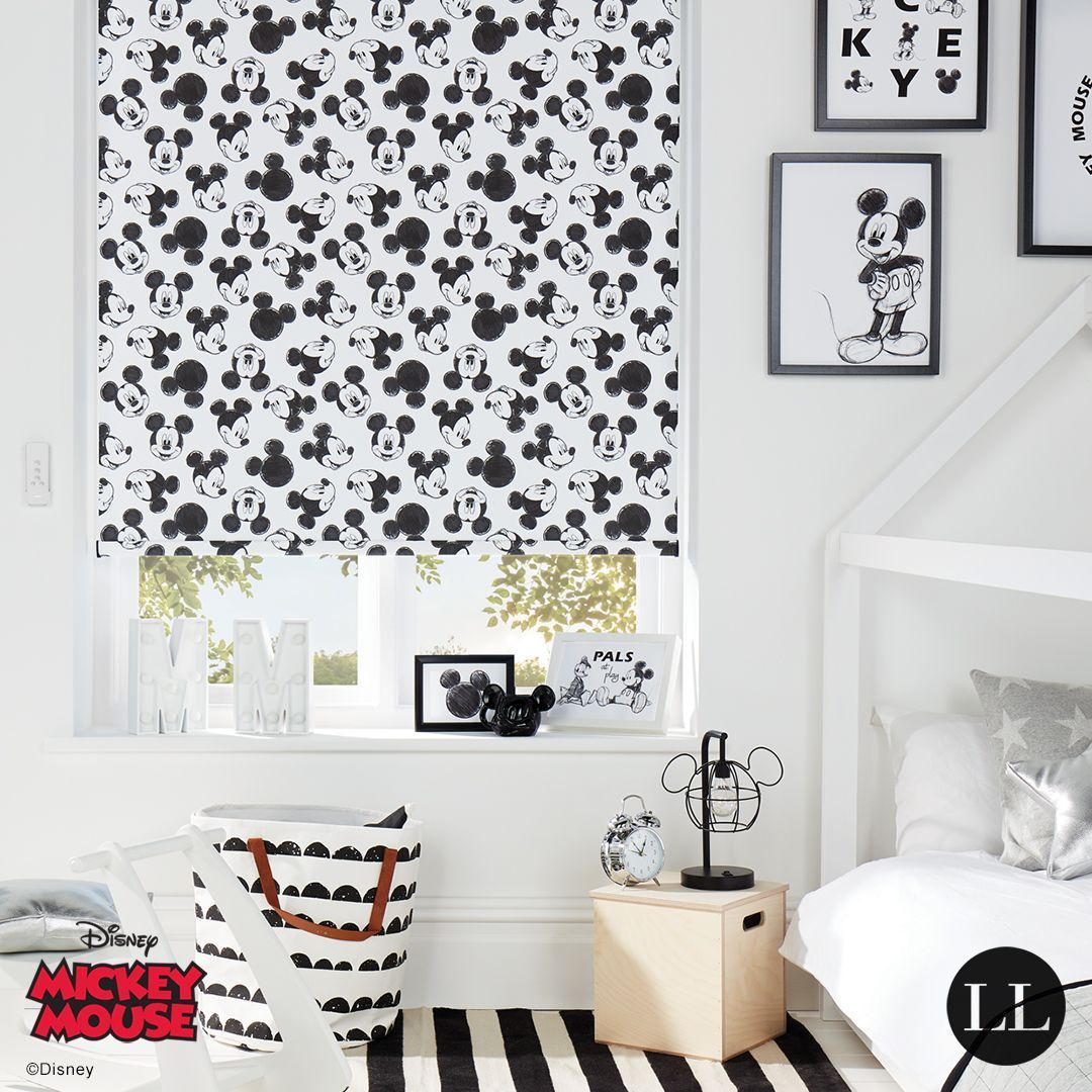 A bedroom with a mickey mouse blind on the window